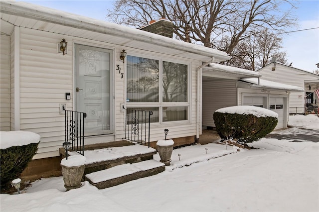 snow covered property entrance with a garage