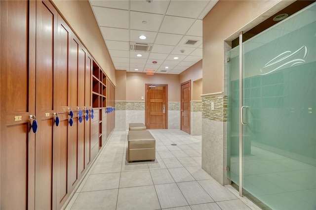 interior space with light tile patterned flooring, a paneled ceiling, and tile walls