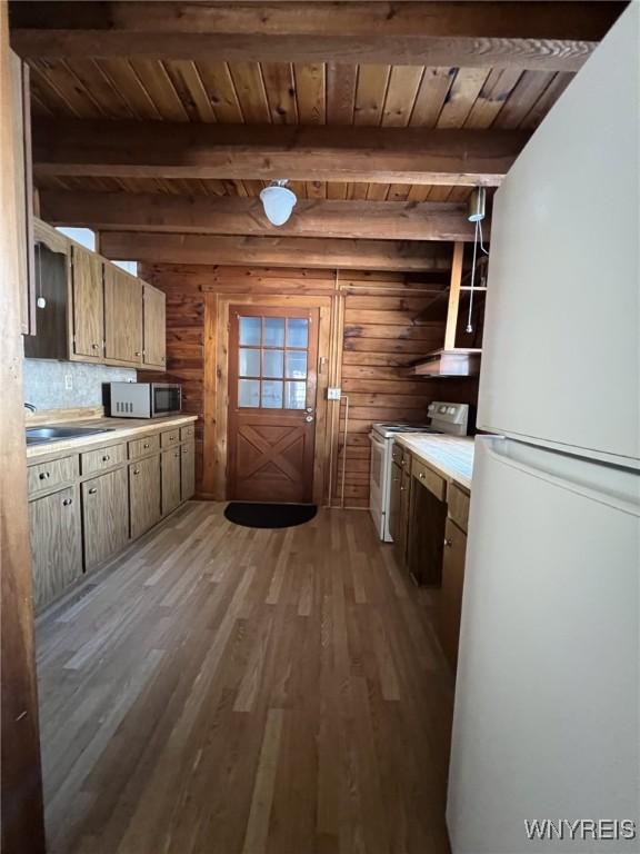 kitchen featuring wooden walls, beamed ceiling, hardwood / wood-style flooring, wood ceiling, and white appliances