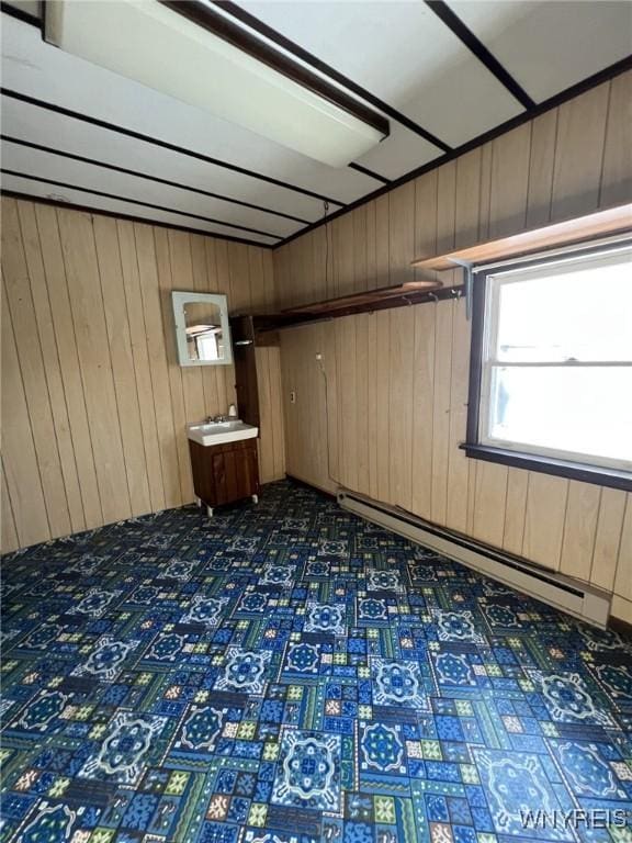 empty room with wood walls, dark floors, and a baseboard heating unit