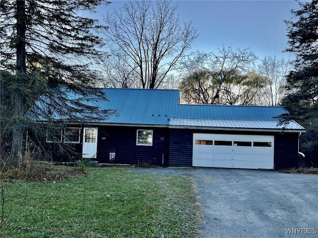 view of front facade with metal roof, a garage, driveway, faux log siding, and a front yard