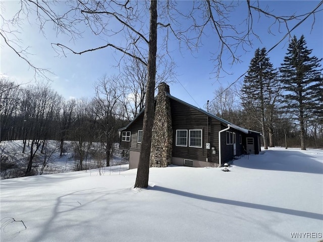 view of snow covered exterior with a chimney