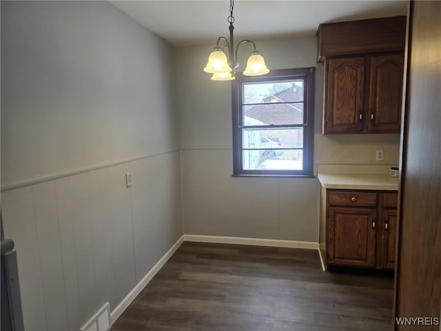 unfurnished dining area featuring a notable chandelier and dark hardwood / wood-style floors