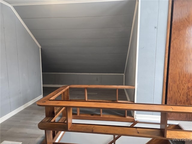 stairs with hardwood / wood-style flooring, lofted ceiling, and wooden walls