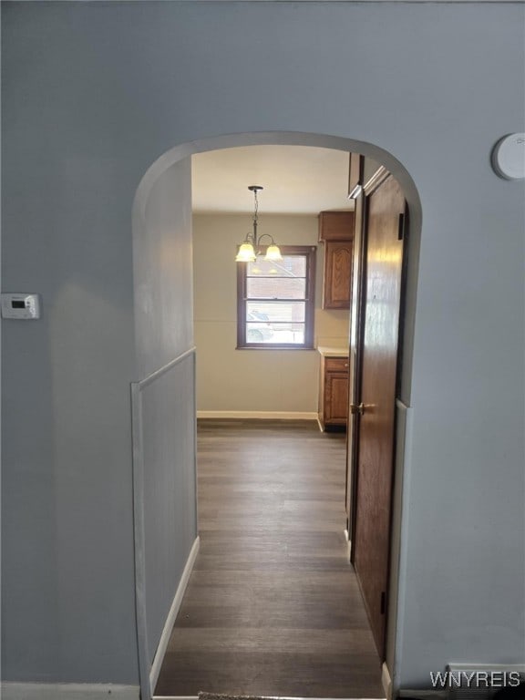 hallway featuring an inviting chandelier and dark wood-type flooring