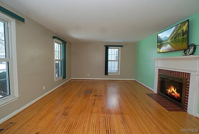 unfurnished living room with a brick fireplace and light hardwood / wood-style flooring