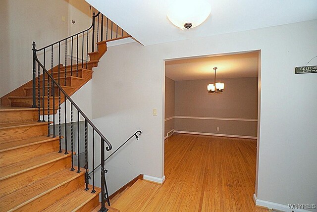 stairs with hardwood / wood-style floors and a notable chandelier