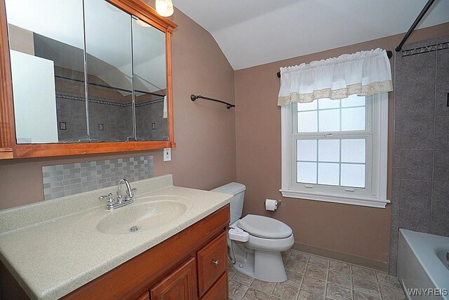 bathroom with tasteful backsplash, lofted ceiling, vanity, and toilet