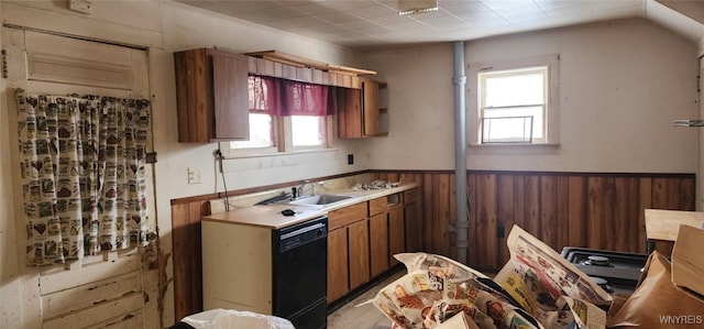 kitchen with sink, black dishwasher, and wood walls