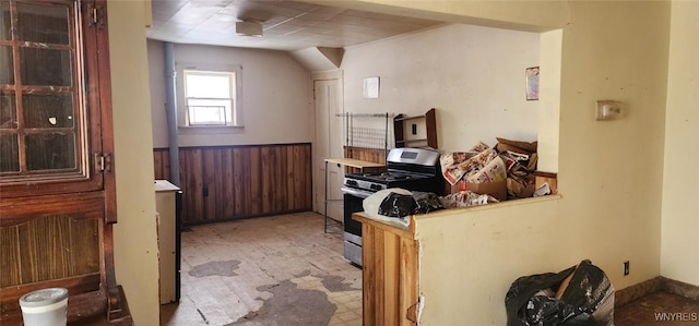 kitchen with stainless steel range with gas stovetop and wood walls