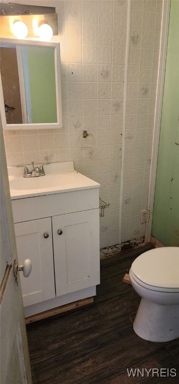 bathroom with tile walls, backsplash, hardwood / wood-style flooring, vanity, and toilet