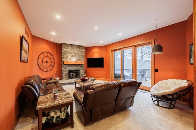 carpeted living room with a stone fireplace