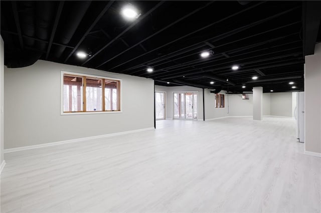 basement with a healthy amount of sunlight and light hardwood / wood-style flooring