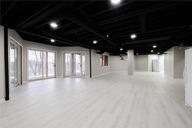 basement with a healthy amount of sunlight and light hardwood / wood-style floors