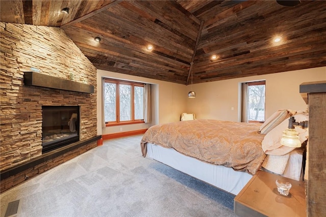 carpeted bedroom featuring a stone fireplace and high vaulted ceiling