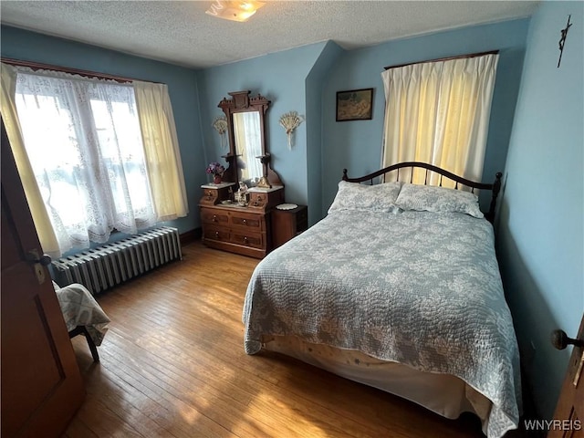 bedroom featuring radiator, a textured ceiling, and light wood-type flooring