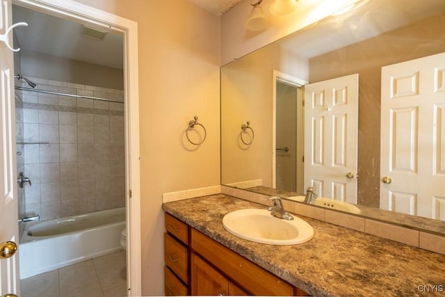 full bathroom with tiled shower / bath combo, vanity, tile patterned floors, and toilet