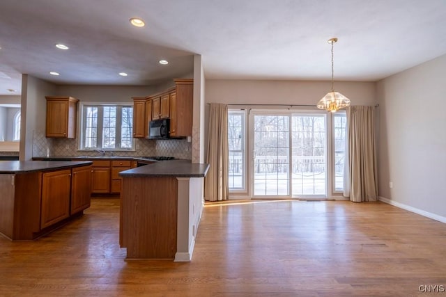 kitchen with plenty of natural light, decorative light fixtures, backsplash, and light hardwood / wood-style flooring