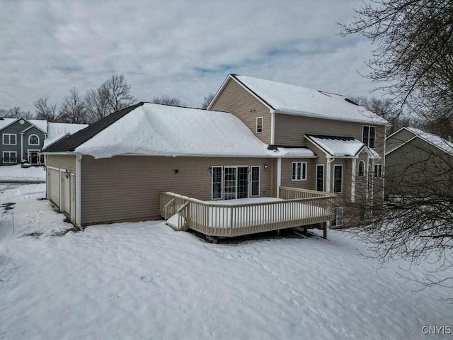 snow covered rear of property with a wooden deck