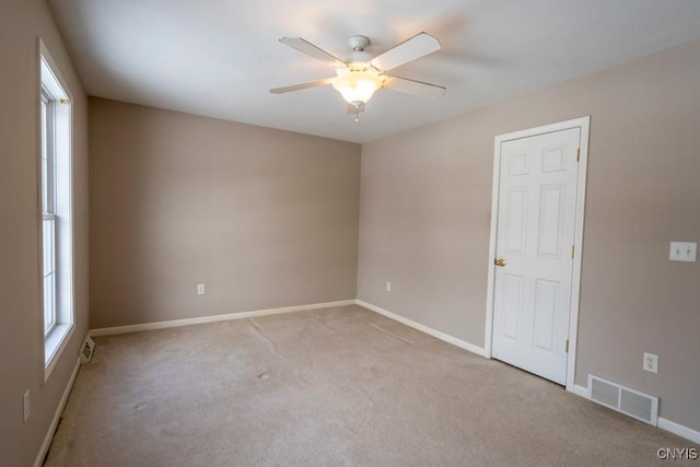 carpeted spare room featuring a healthy amount of sunlight and ceiling fan