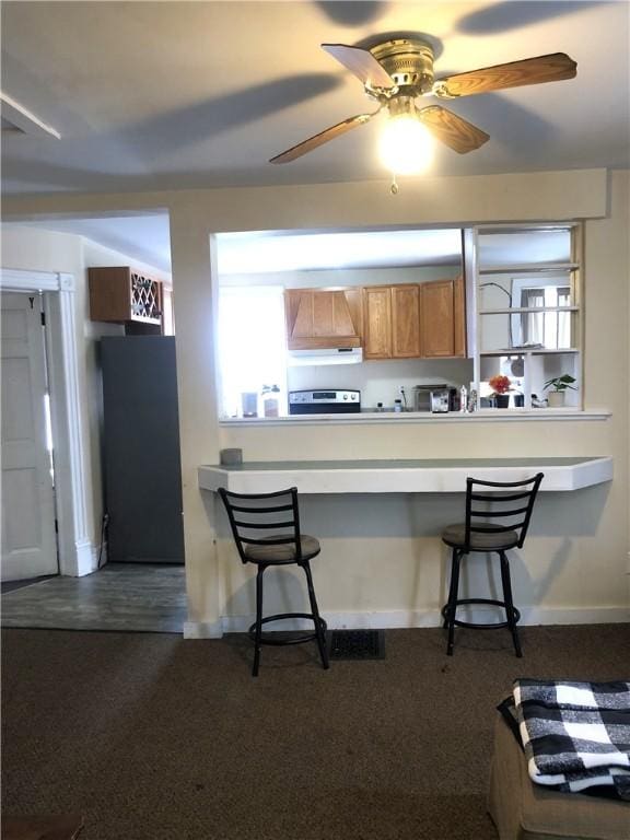 kitchen featuring custom exhaust hood, a breakfast bar, refrigerator, and stainless steel electric range