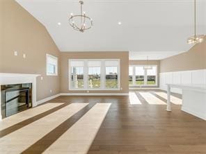 unfurnished living room featuring a towering ceiling, dark hardwood / wood-style floors, and a notable chandelier