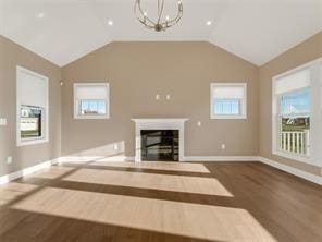 unfurnished living room featuring lofted ceiling, hardwood / wood-style floors, and a notable chandelier