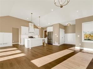 kitchen featuring stainless steel refrigerator, ventilation hood, a center island, and hanging light fixtures