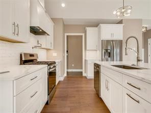 kitchen featuring sink, white cabinetry, ventilation hood, appliances with stainless steel finishes, and pendant lighting