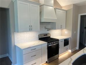 kitchen featuring premium range hood, white cabinetry, stainless steel gas range, and light stone countertops