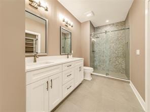 bathroom with vanity, toilet, and a tile shower