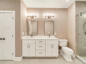 bathroom featuring tile patterned flooring, vanity, toilet, and a shower with shower door