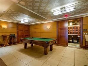 rec room with light tile patterned floors, pool table, and wood walls