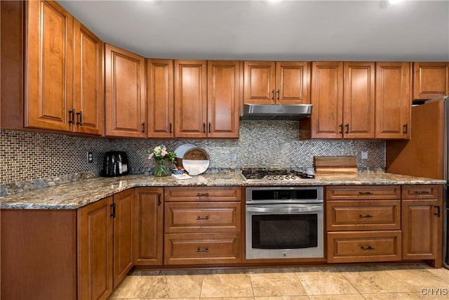 kitchen with appliances with stainless steel finishes, light stone countertops, and decorative backsplash