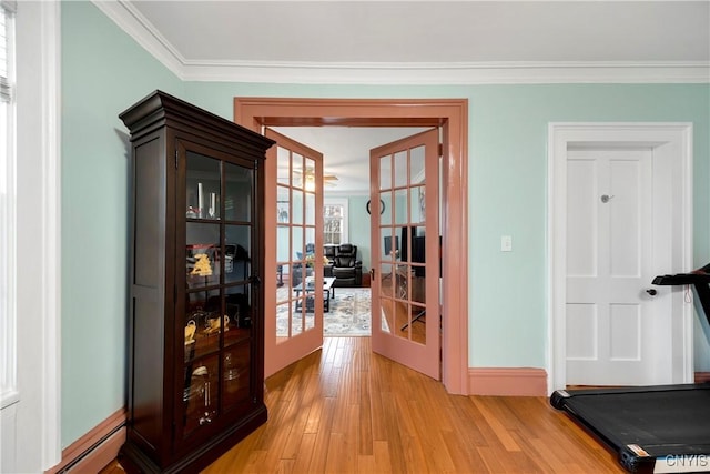 interior space with ornamental molding, a baseboard heating unit, light wood-type flooring, and french doors