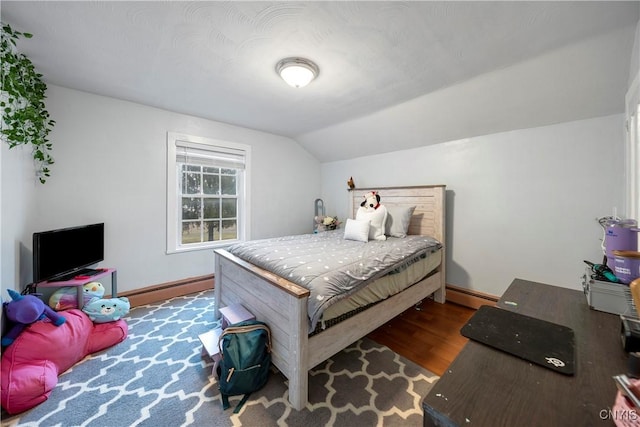 bedroom with baseboard heating, vaulted ceiling, and dark wood-type flooring