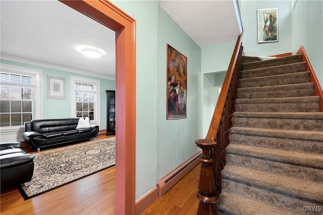 stairway with wood-type flooring, ornamental molding, and baseboard heating