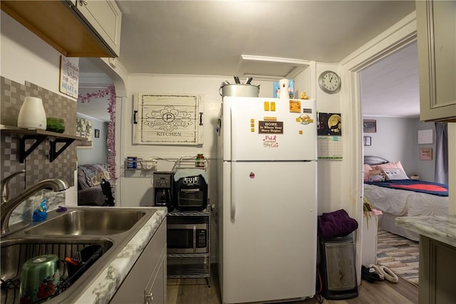 kitchen featuring sink, crown molding, light wood-type flooring, and white fridge