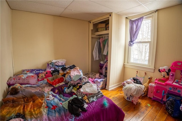 bedroom featuring a drop ceiling, hardwood / wood-style flooring, and a closet