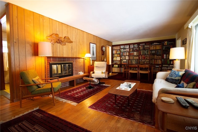 living area with hardwood / wood-style floors, a fireplace, and wood walls