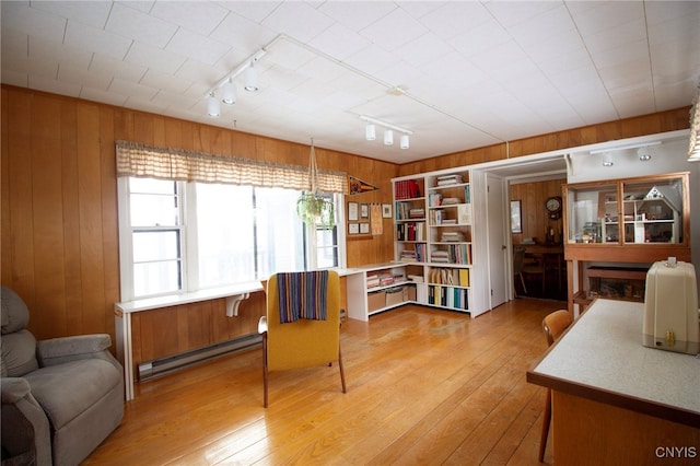 living area featuring wooden walls, light hardwood / wood-style floors, rail lighting, and a baseboard heating unit