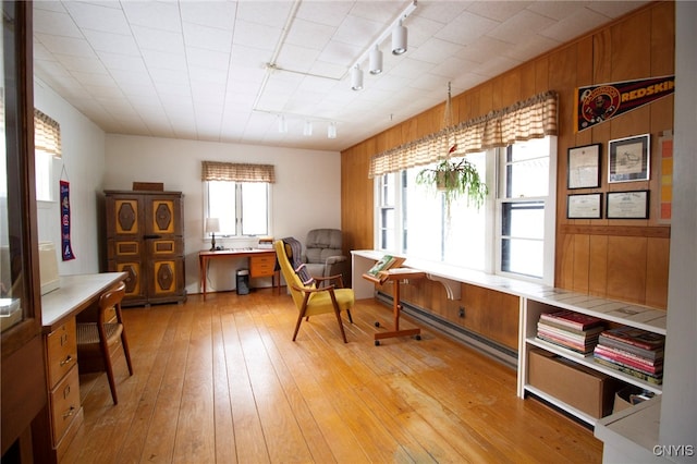 sitting room featuring wooden walls, rail lighting, light hardwood / wood-style flooring, and a baseboard radiator