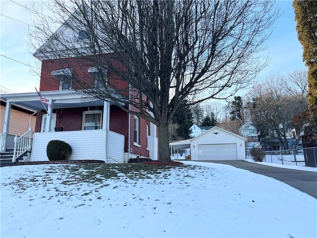 view of snowy exterior featuring an outbuilding and a garage