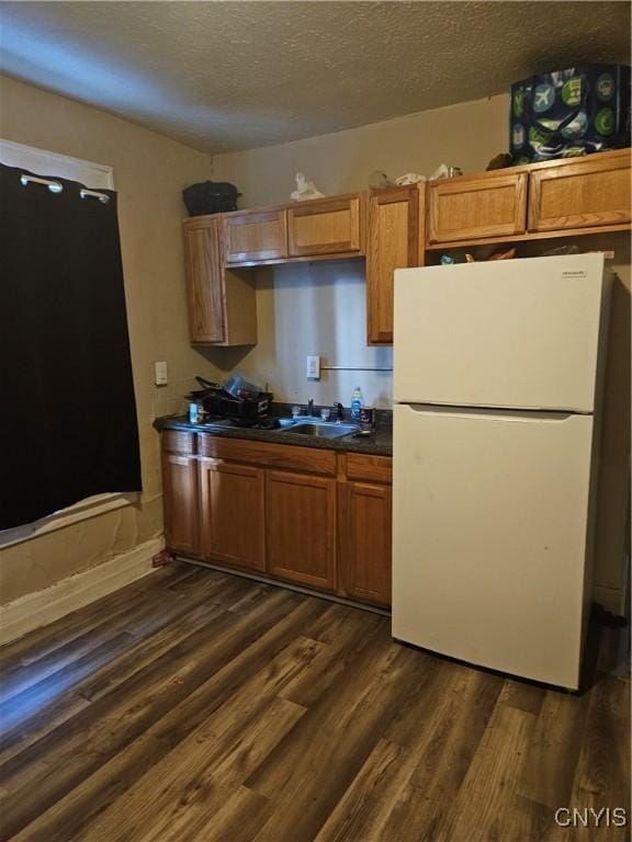 kitchen featuring white refrigerator, dark wood-type flooring, sink, and a textured ceiling