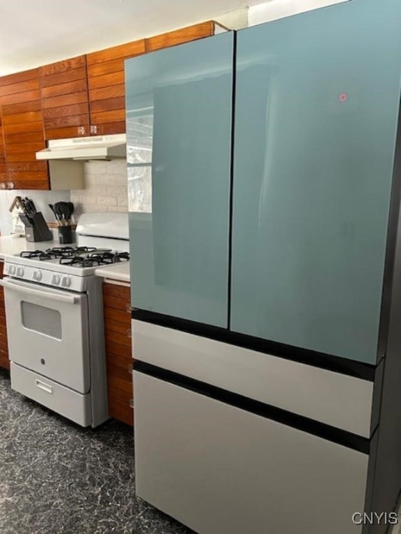 kitchen with tasteful backsplash, fridge, and white gas range oven