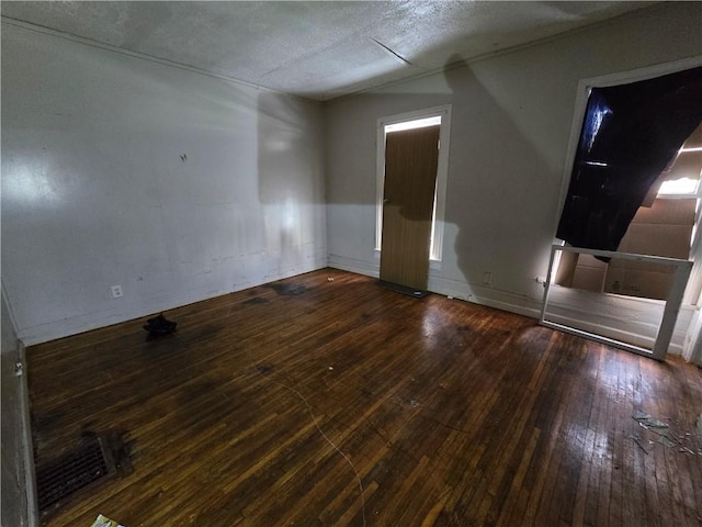 spare room featuring dark hardwood / wood-style floors and a textured ceiling