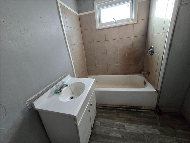 bathroom featuring hardwood / wood-style flooring, tiled shower / bath, and vanity