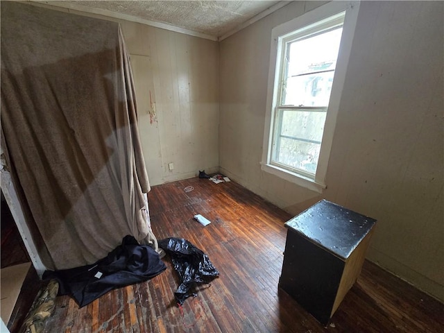 empty room with a wealth of natural light, dark wood-type flooring, and ornamental molding