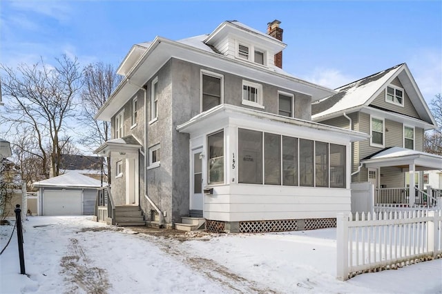 view of front facade featuring an outbuilding, a garage, and a sunroom