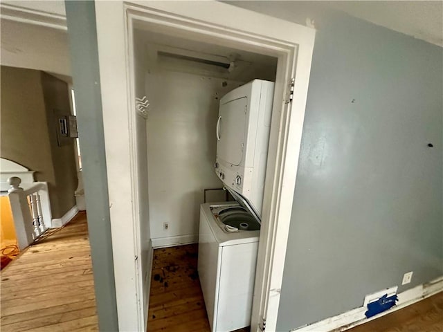 laundry room with stacked washing maching and dryer and light hardwood / wood-style floors